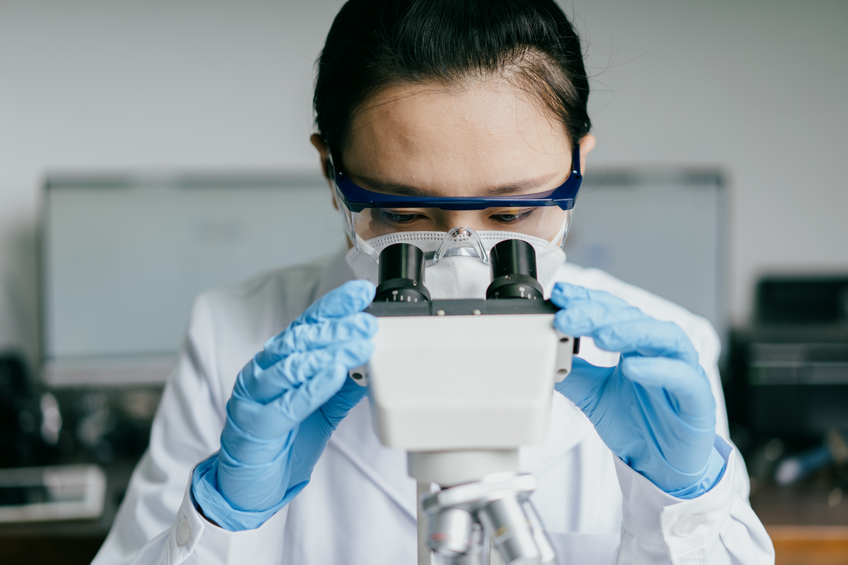 Scientist looking into a microscope. The camera is pointing directly at the scientist